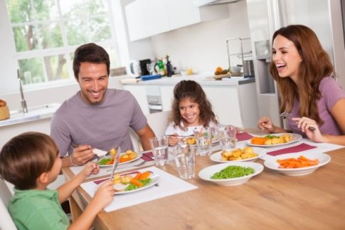 famiglia seduta a tavola mangiare sano
